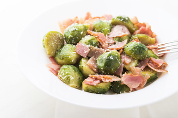 Brussels sprouts with bacon and parmesan on white background close up.