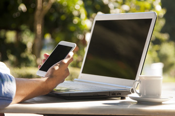 hand with mobile phone on the notebook computer