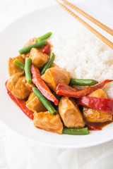 Spicy chicken with vegetables ( green beans and red pepper) and rice close up. Oriental food.