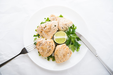 Chicken breasts with parsley and citrus on white background top view. Healthy food.