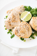 Chicken breasts with parsley and citrus on white background close up. Healthy food.
