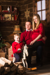 Fototapeta na wymiar Young pregnant mother, father and small son celebrating Christmas at home