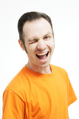 Close-up portrait of guy winking open-mouthed. Over white background. Winking guy with opened mouth . Crazy guy in an orange T-shirt.