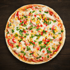 Pizza with mozzarella cheese, chicken, sweet corn, sweet pepper and parsley on dark wooden background top view. Italian cuisine.