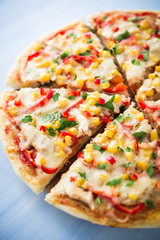 Colorful sliced pizza with mozzarella cheese, chicken, sweet corn, sweet pepper and parsley close up. Italian cuisine.