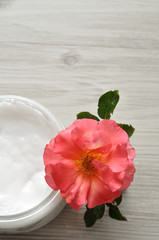 Body lotion in a plastic container with a pink rose top view