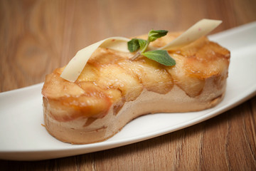 Apple pie with mint on a white plate on a wooden background