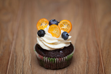 Delicious cupcakes with berries on wooden table close up
