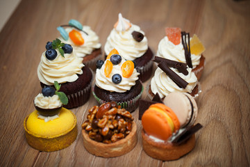 Nine different cakes standing on a wooden table