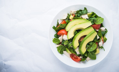 Fresh salad with chicken, tomatoes, spinach and avocado on white background top view. Healthy food. Space for text.