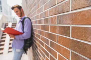 Joyful male student learning lesson outdoors