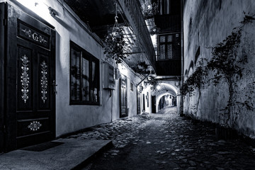 Moody monochrome view of a cobblestone street passage in the old city center of Sibiu, Romania