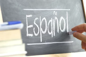 Foto op Canvas Hand writing on a blackboard in a language class with the word "Spanish" written on it. Some books and school materials. © JuanCi Studio