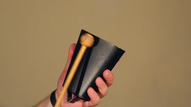 One Man Playing on the Percussion Instrument Cowbell. on the Bright Walls Background.