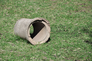 Plumbing pipe made of concrete on the lawn. Tube positioned left.