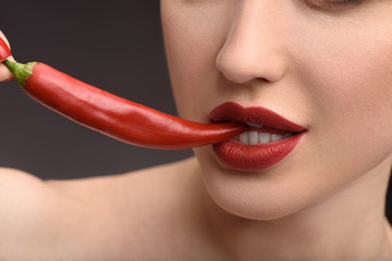 Obraz premium Passionate woman biting hot chili