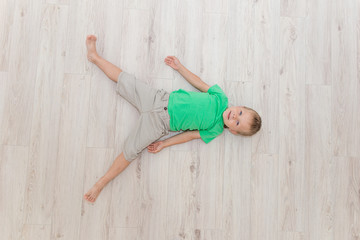 Little handsome boy with blue eyes lying on the floor