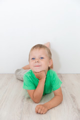 Naklejka premium Little handsome boy with blue eyes lying on the floor