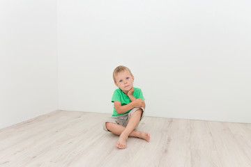 Naklejka premium Little cute boy sitting on the floor