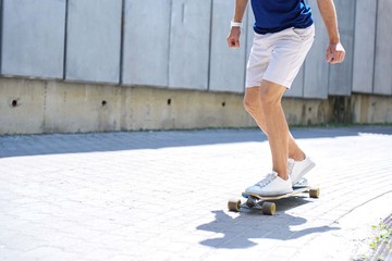 Cheerful guy riding skateboard on road