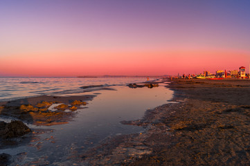 Mare, spiaggia al tramonto con cielo rosso. Sea, beach at sunset with red sky
