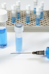 Vials of blue liquid and a syringe on bench