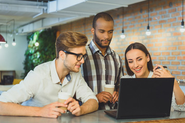 Carefree men and woman using laptop in cafeteria