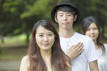 Naklejka premium 若者 男女 3人 ポートレイト 真剣カメラ目線 屋外 緑 公園 20代