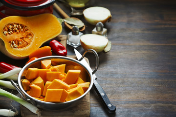 Preparing pumpkin, onions and sweet peppers for cooking