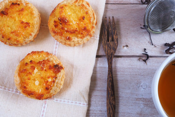 Close up of Coconut tarts with dried tea leaves on a wooden table.