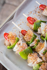 Chicken kebabs on a baking sheet seasoned and ready for grilling
