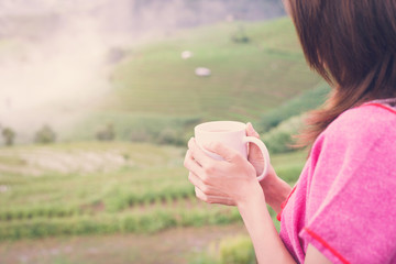 Woman holding a cup of coffee with beautiful landscape