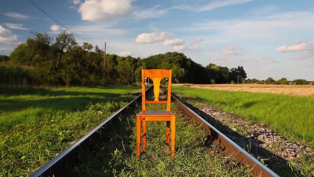 Railroad tracks and old wooden chair at sunset