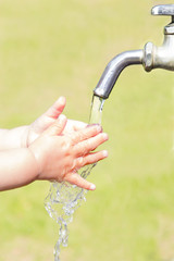 水道で手を洗っている幼児の小さな手
