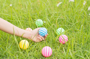 Fototapeta premium Close up young woman playing ball in the garden.Close up young woman playing colorful plastic balls for kid activity.
