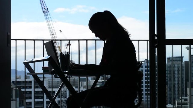 Side view Silhouette of Young woman (age 30-40) having back pain while working at desk in office. Woman work healthcare lifestyle concept. Real people. copy space