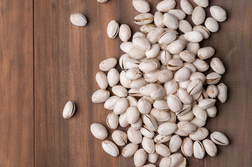 Roasted and salted pistachios in shell on wooden background