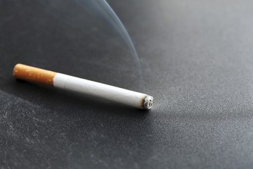 Cigarette with ash on black background