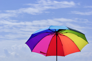 Beautiful Rainbow umbrella on bright sky background.