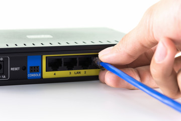 hand connecting a yellow network cable on a network port of a router.