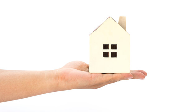 hand holding a house model on a white background