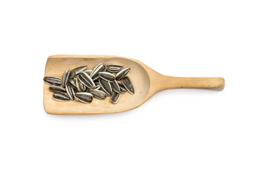 Some striped sunflower seeds on a wooden spoon with white background seen from above