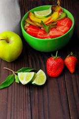 Oatmeals in green plate decorated with slice of strawberry, kiwi peach and lime. Bottle of milk and glass of milk, green apple lime with mint.On dark wooden background.Top view.Flat lay.