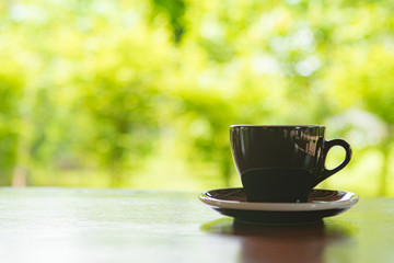A black cup of coffee on table in cafe ,Morning light