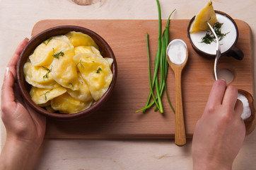 Woman hands impaled  vareniks (dumpling) on fork get wet on sour