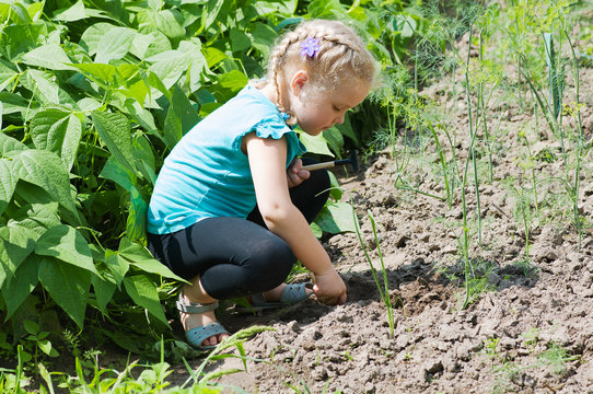 Girl child in rays planting seeds on farm in bed