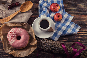 fresh donut with coffee on wooden table with napkin, spoon and c