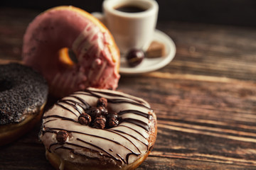 fresh donut with coffee on wooden table with napkin, spoon and c