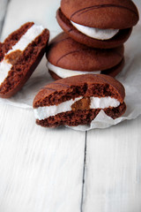 Broken cookies and stack of sponge cookies with cream on paper. vertical shot.Selective focus