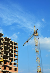 Crane and building construction site against blue  sky with clouds